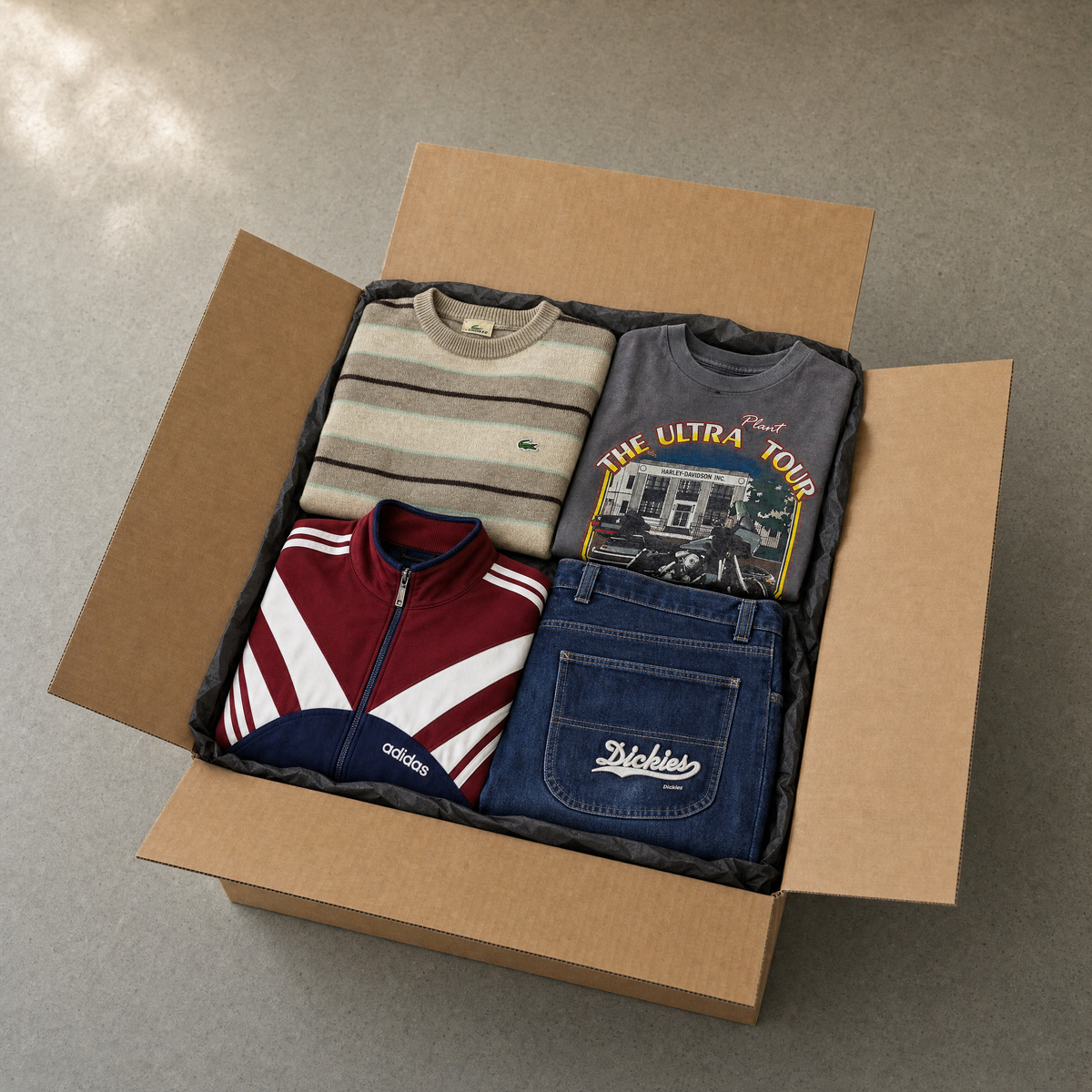 Vintage Mystery Box Komplettes Outfit – geöffnete Kraftkarton-Box mit gefaltetem Vintage-Outfit: Sweater, Shirt, Jacke, Jeans
