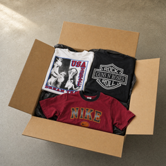 Vintage Mystery Box T-Shirts – geöffnete Kraftkarton-Box mit gefalteten Second-Hand-Shirts